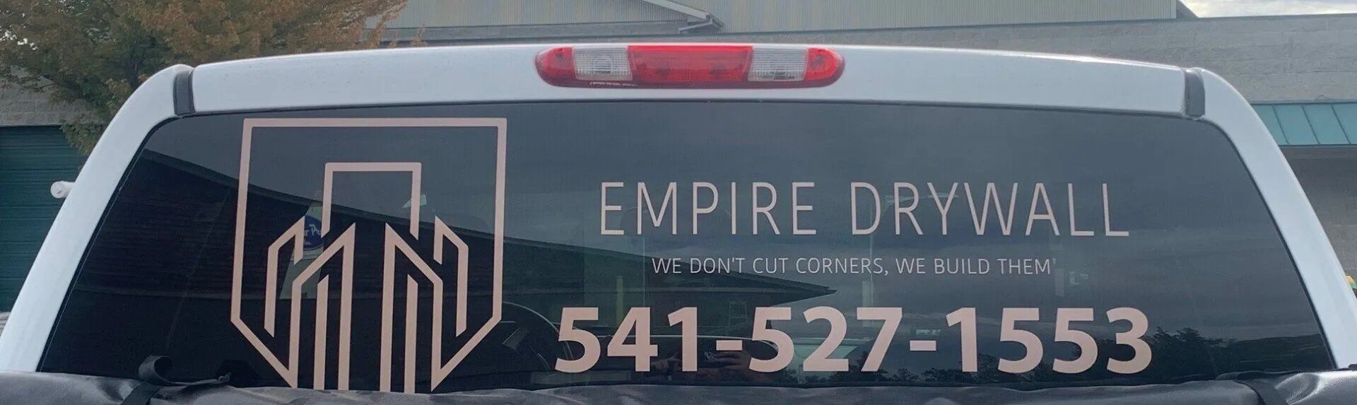 A white truck with empire drywall written on the back window