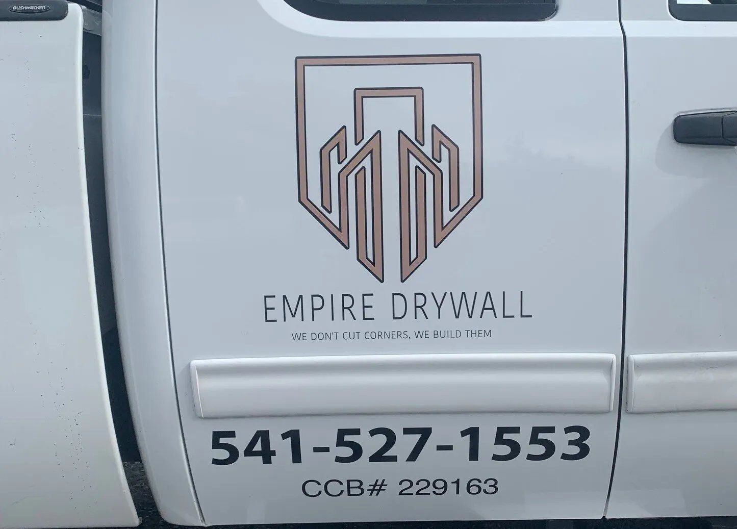 A white truck with empire drywall written on the side