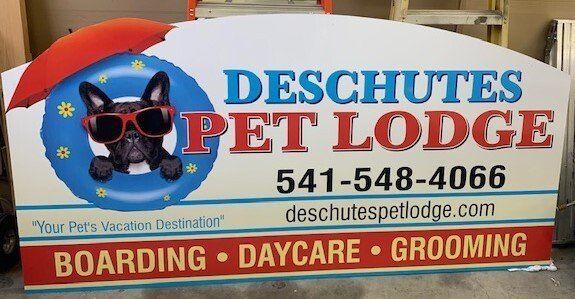 A sign for deschutes pet lodge shows a dog wearing sunglasses