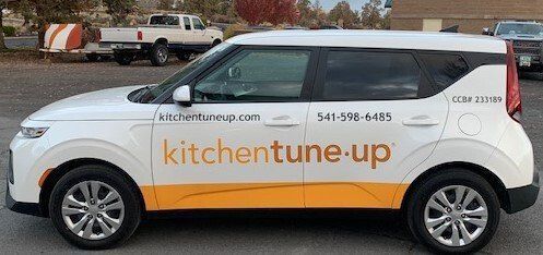 A white car with a yellow stripe on the side is parked in a parking lot.