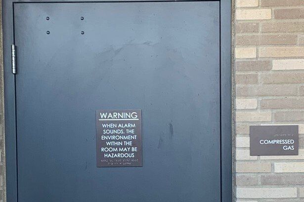 A black door with a warning sign on it