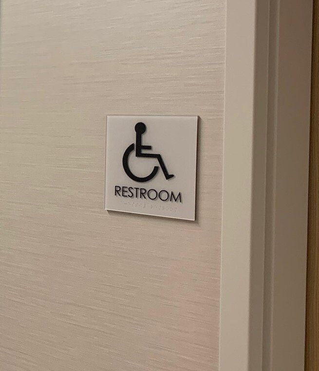 A handicapped restroom sign is hanging on a door.