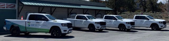 A row of white trucks are parked in front of a building.