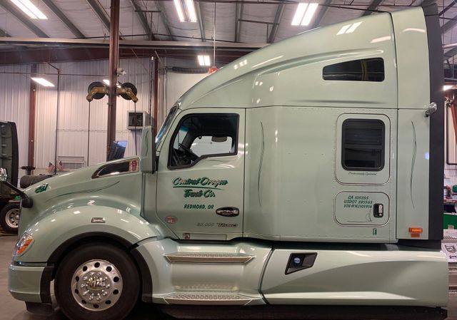 A green semi truck is parked in a garage.