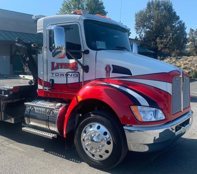 A red and white towing truck is parked in front of a building