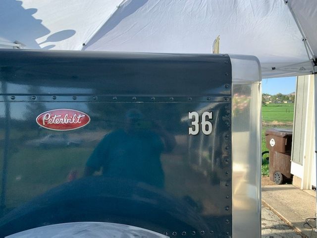 A peterbilt truck is parked under a white tent.
