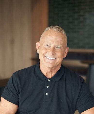 Ghaus founder wearing a black polo shirt is smiling for the camera.