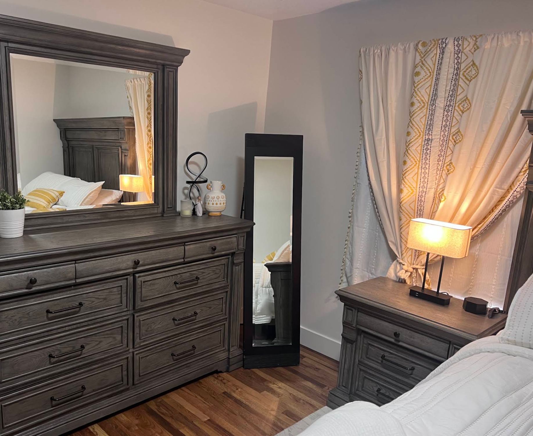 Finished bedroom with white bedding and boho curtains after complete remodel