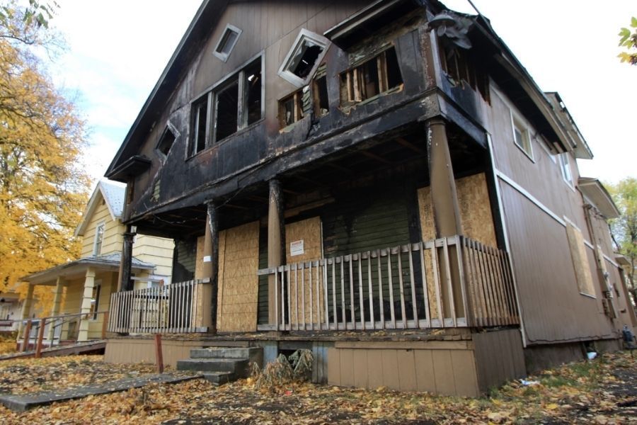 Emergency board-up services securing a fire-damaged property with plywood panels over windows and openings