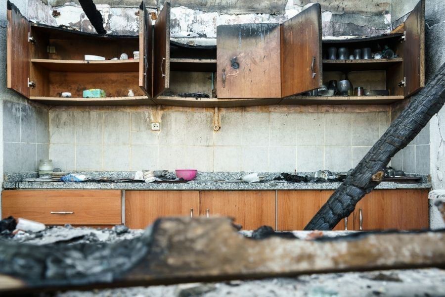 Burnt kitchen elements showing charred cabinets and heat-damaged surfaces after a house fire