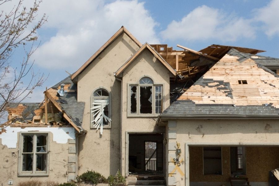 Compromised roof structure with visible fire damage and charred trusses after a residential house fire