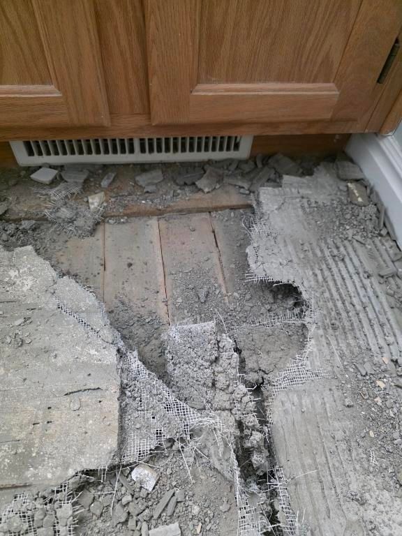 Flooring removal in kitchen area after sewage backup revealing subfloor damage