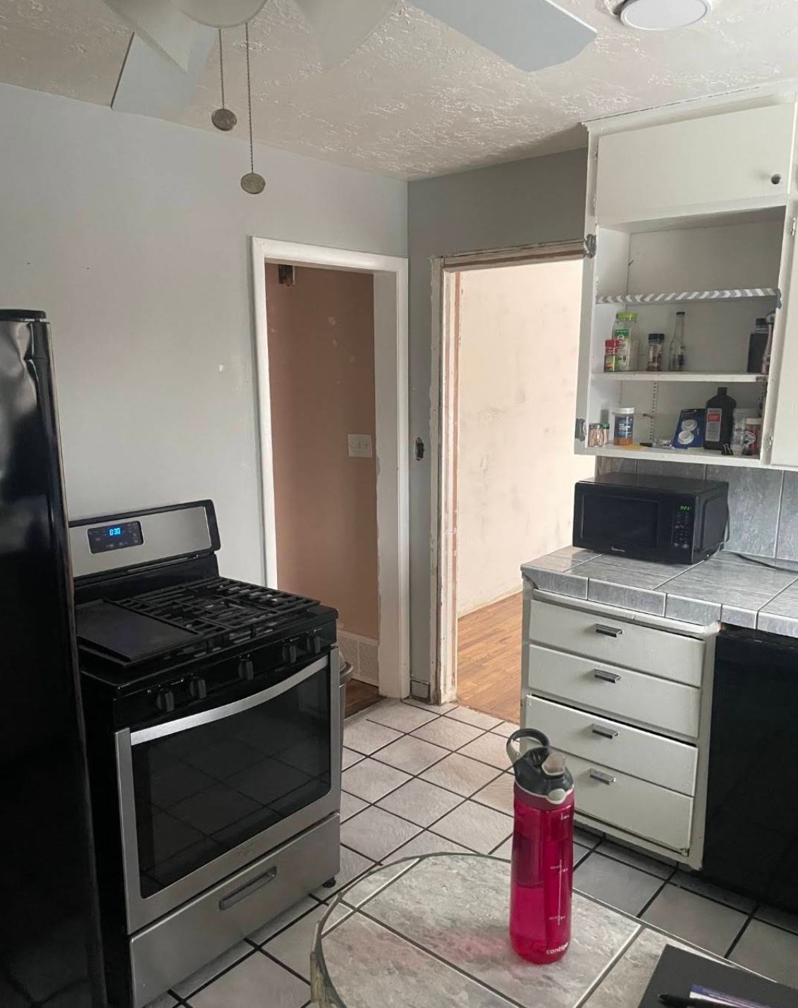 Old built-in pantry shelving with damaged drywall framing in hallway before remodel