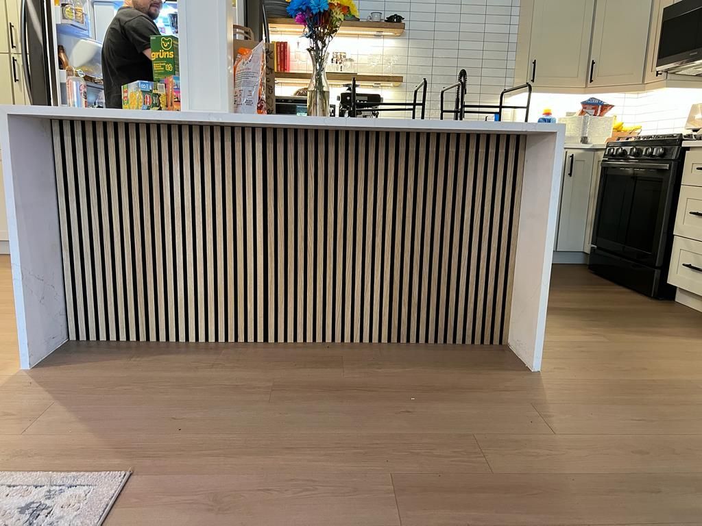 Rebuilt kitchen island with decorative vertical slat panel and new flooring