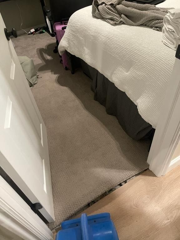 Sewage backup damage visible on bedroom carpet near baseboards in Millcreek condo