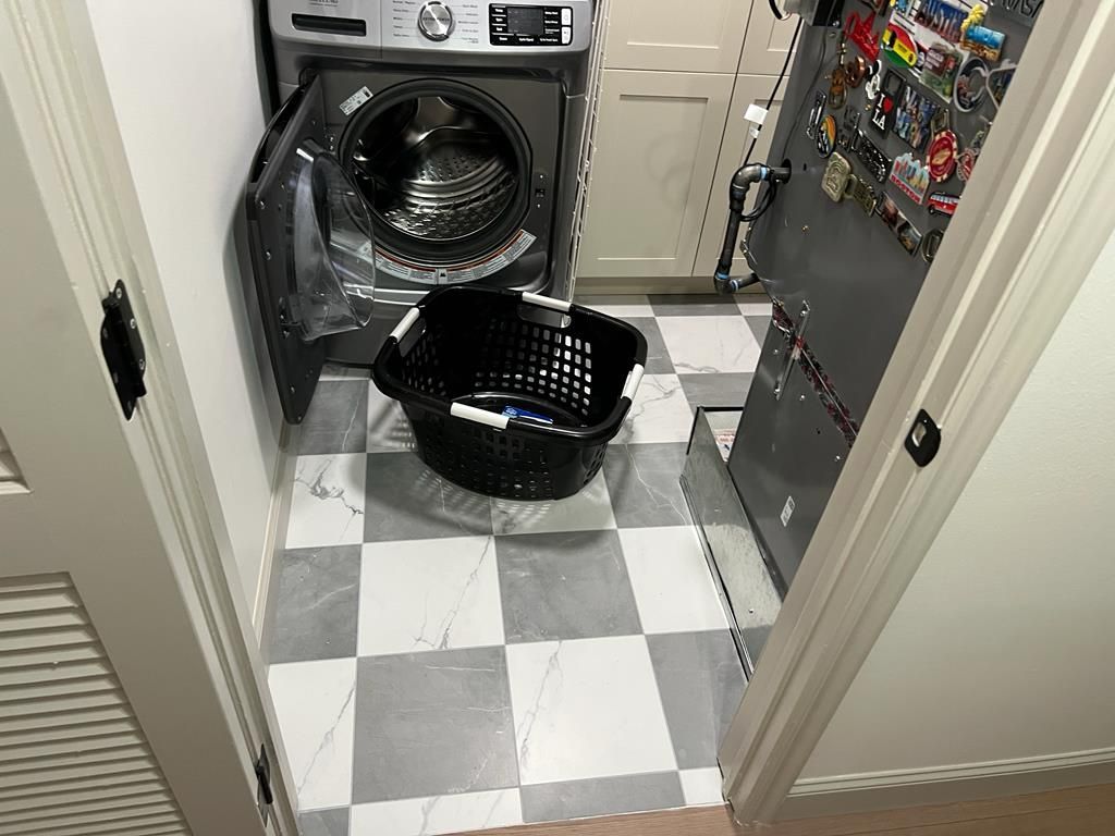 Fully restored laundry area with new checkered tile flooring after sewage backup repair