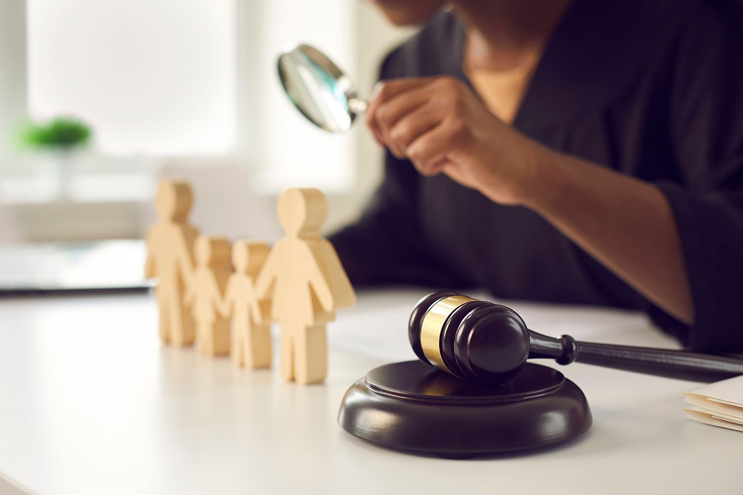 A courtroom gavel beside wooden family figures as legal documents are reviewed at a desk. A courtroom gavel beside wooden family figures as legal documents are reviewed at a desk.