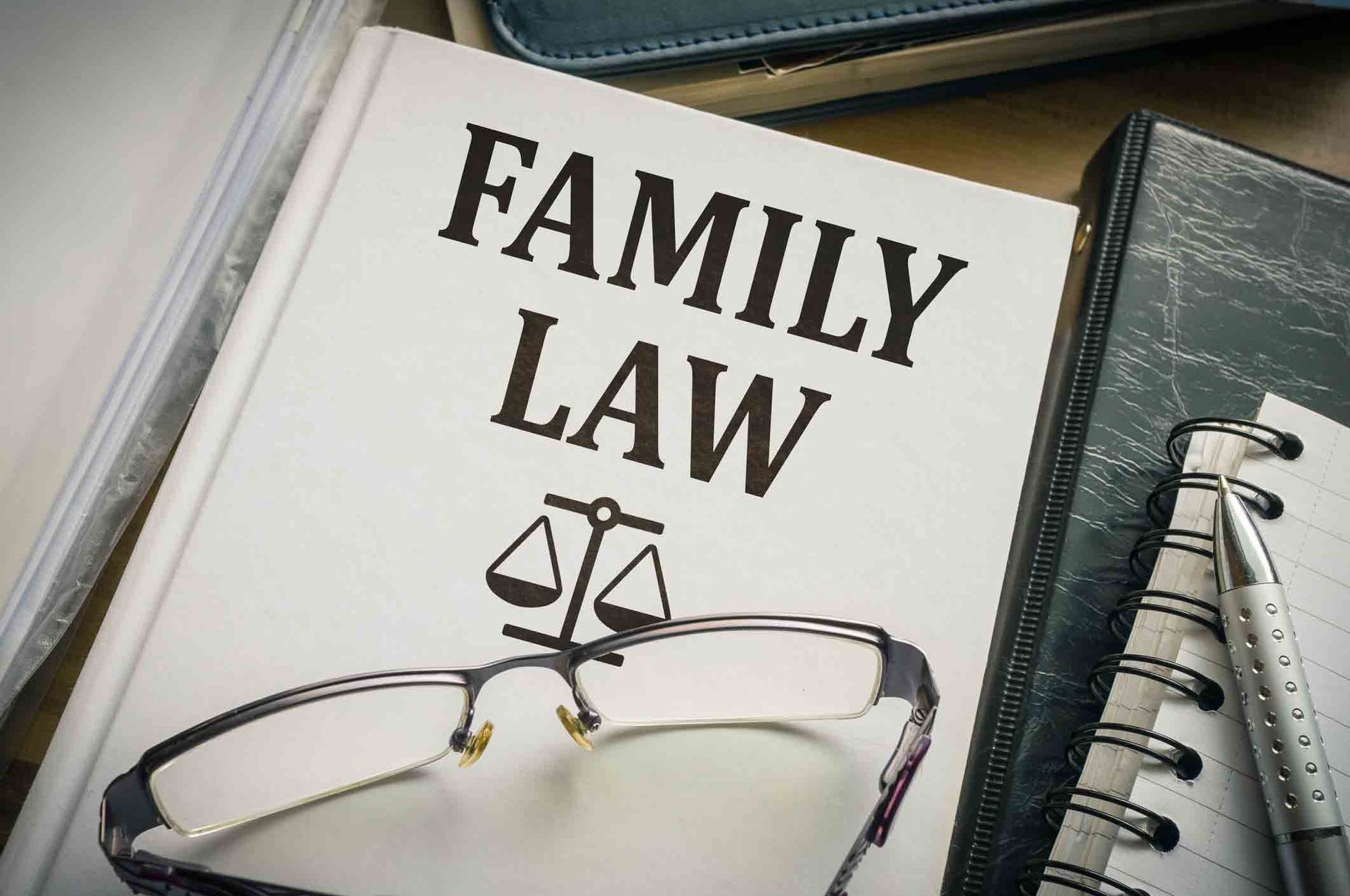A book titled family law with glasses and a scale of justice on it.