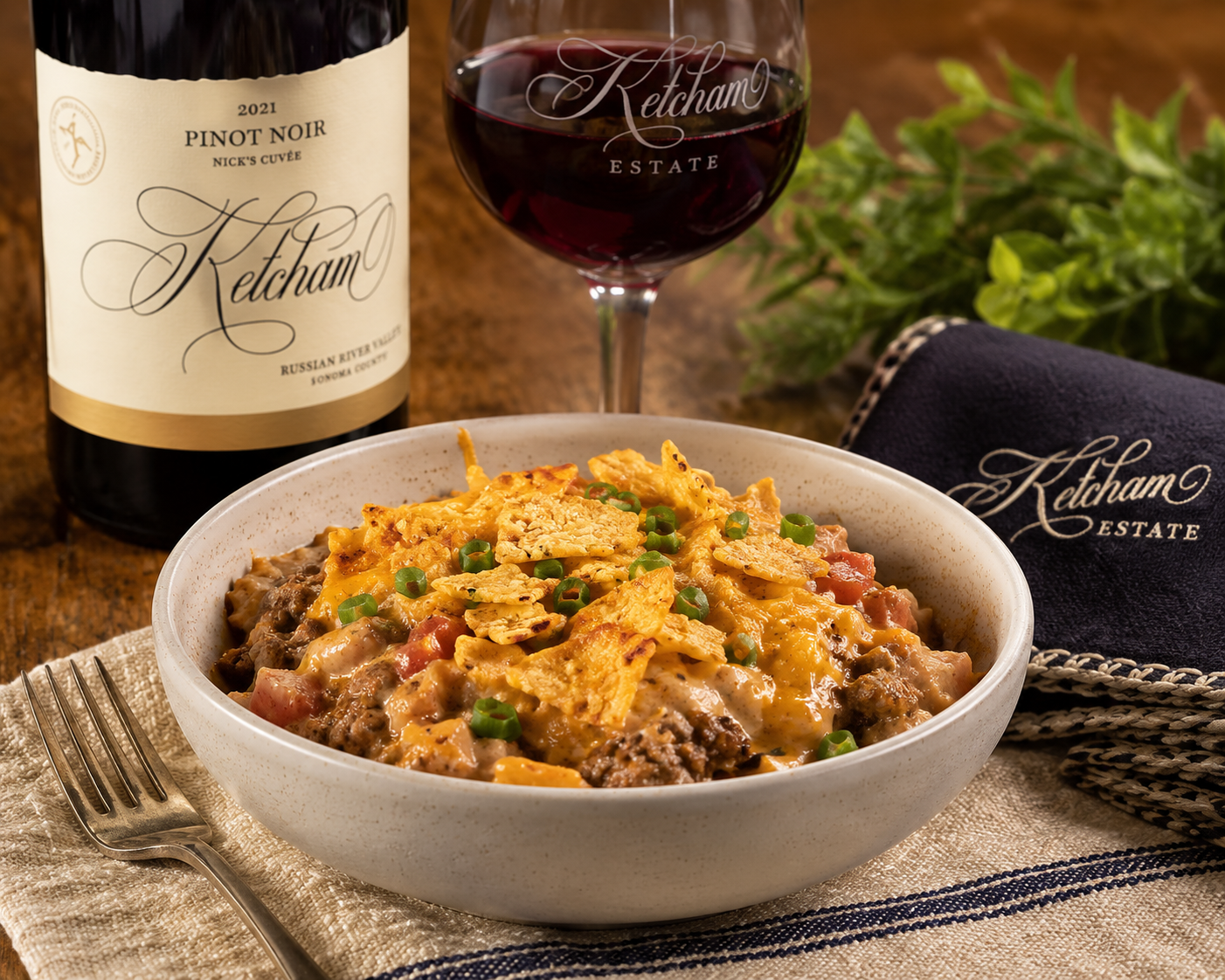 Wine bottle and glass beside a bowl of cheesy taco casserole