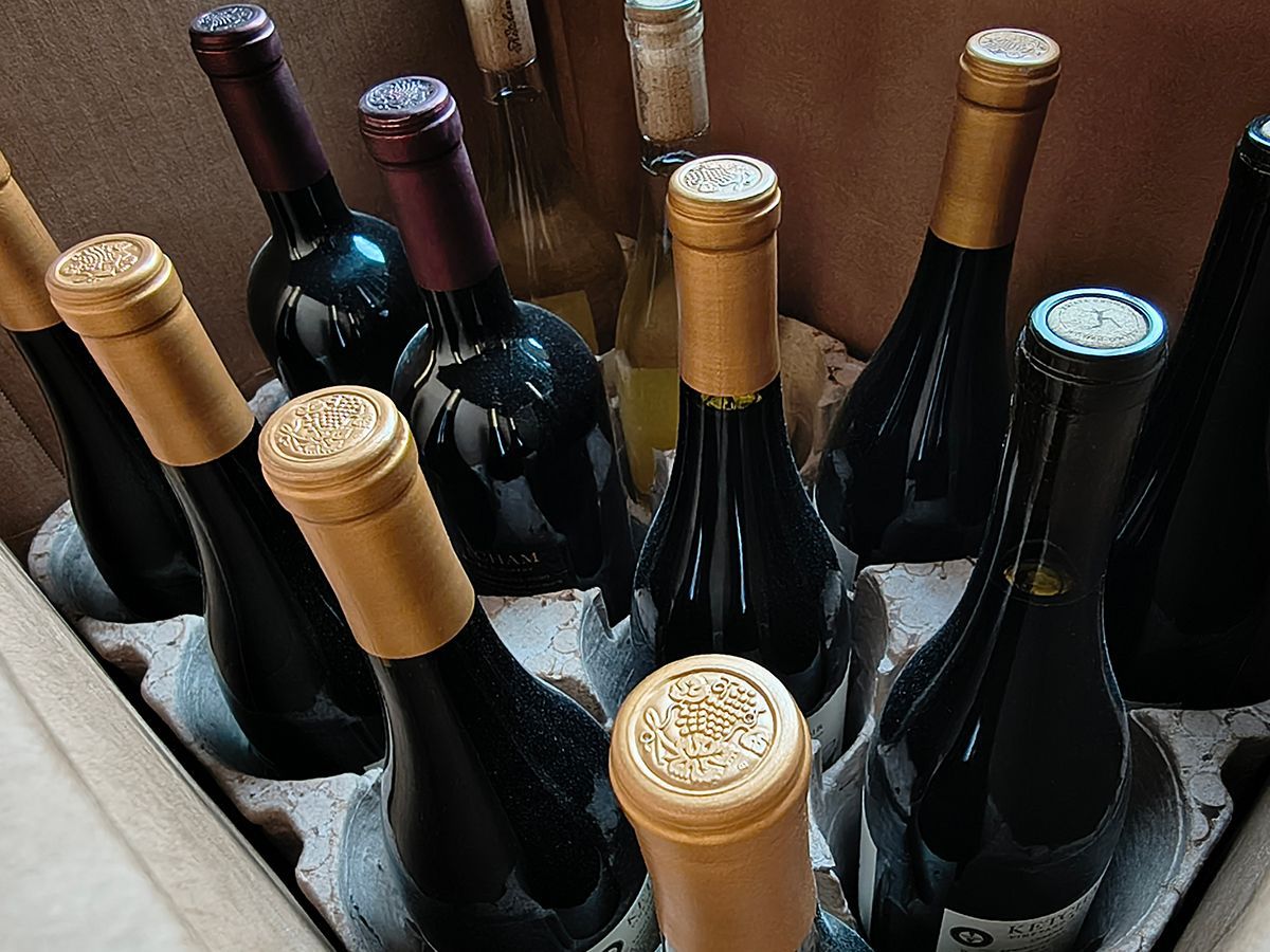 Box of assorted wine bottles with gold foil tops packed upright in cardboard dividers