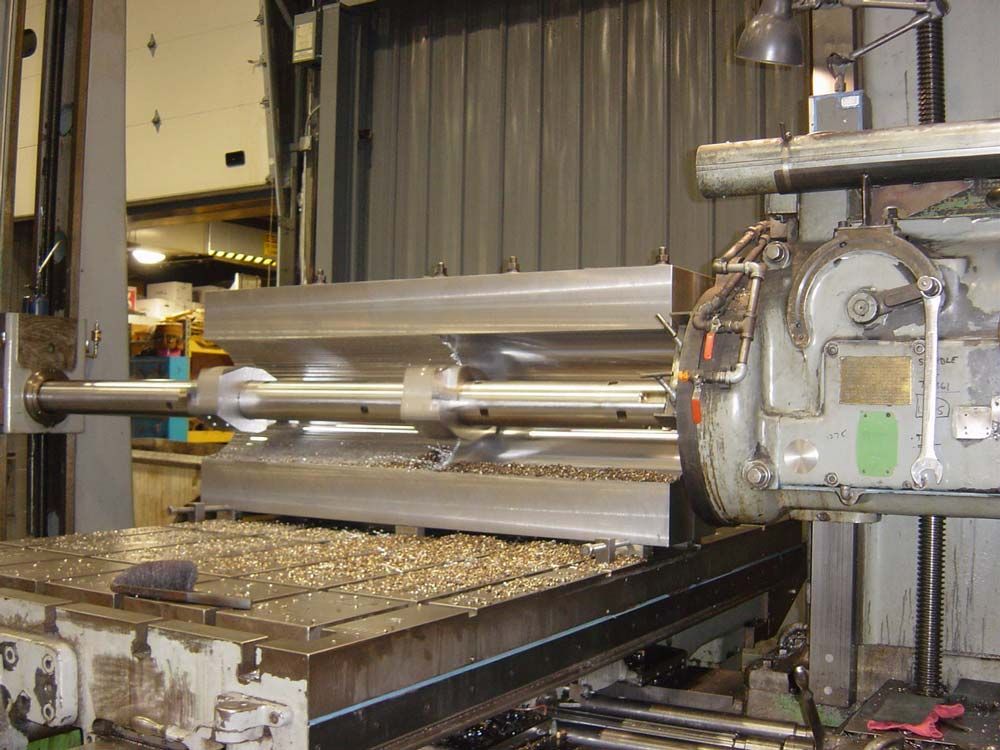 Industrial machine cutting or shaping a large metal sheet in a factory workshop.