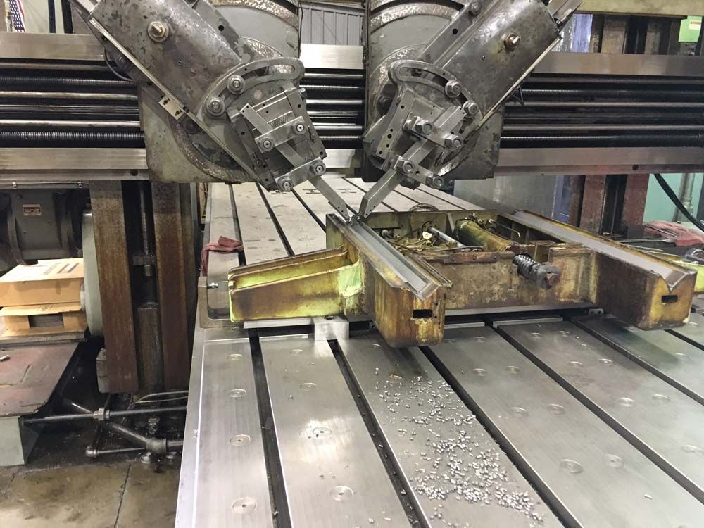CNC machine with dual cutting heads carving a wooden panel on a metal worktable