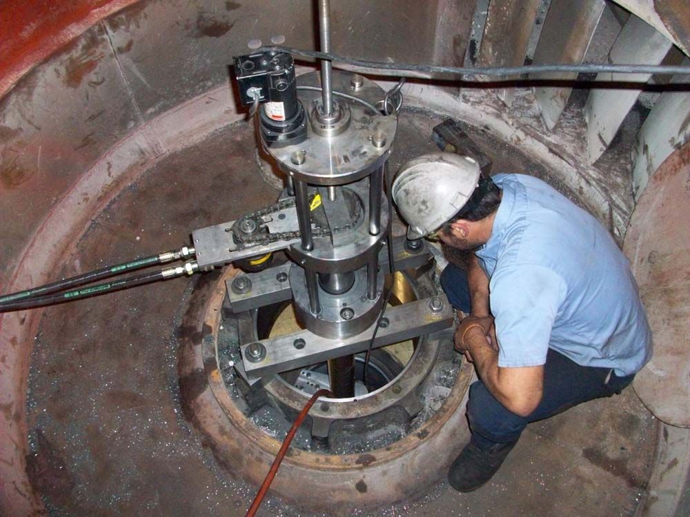 Worker in hard hat inspecting machinery inside a large circular tank or manhole