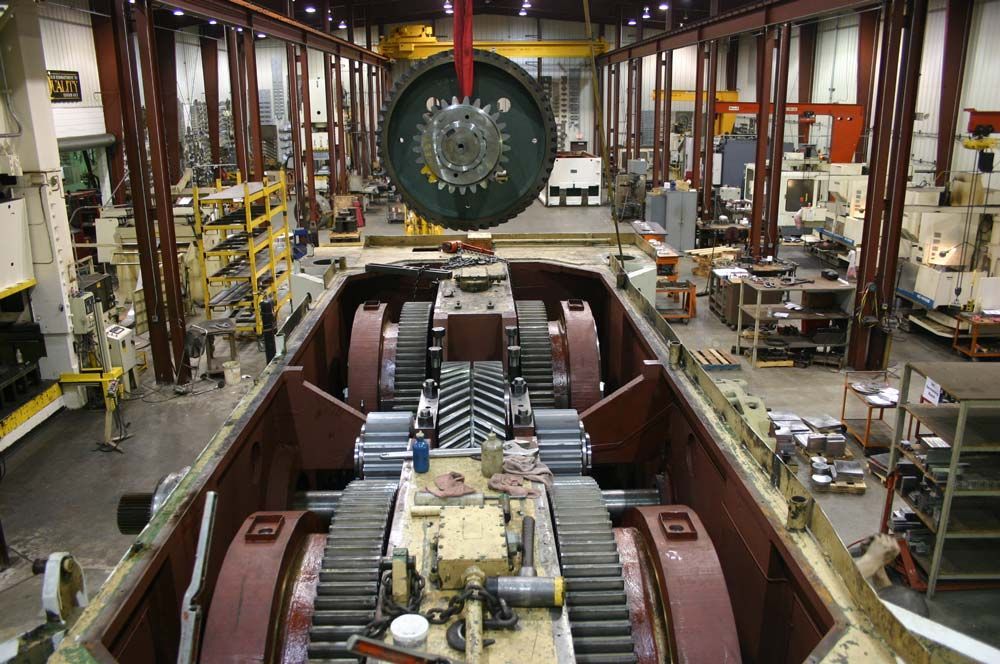 Large industrial workshop with a centered circular machine part and assembly equipment on both sides