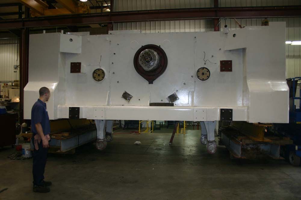 Large white industrial machine in a workshop, with a man standing beside it