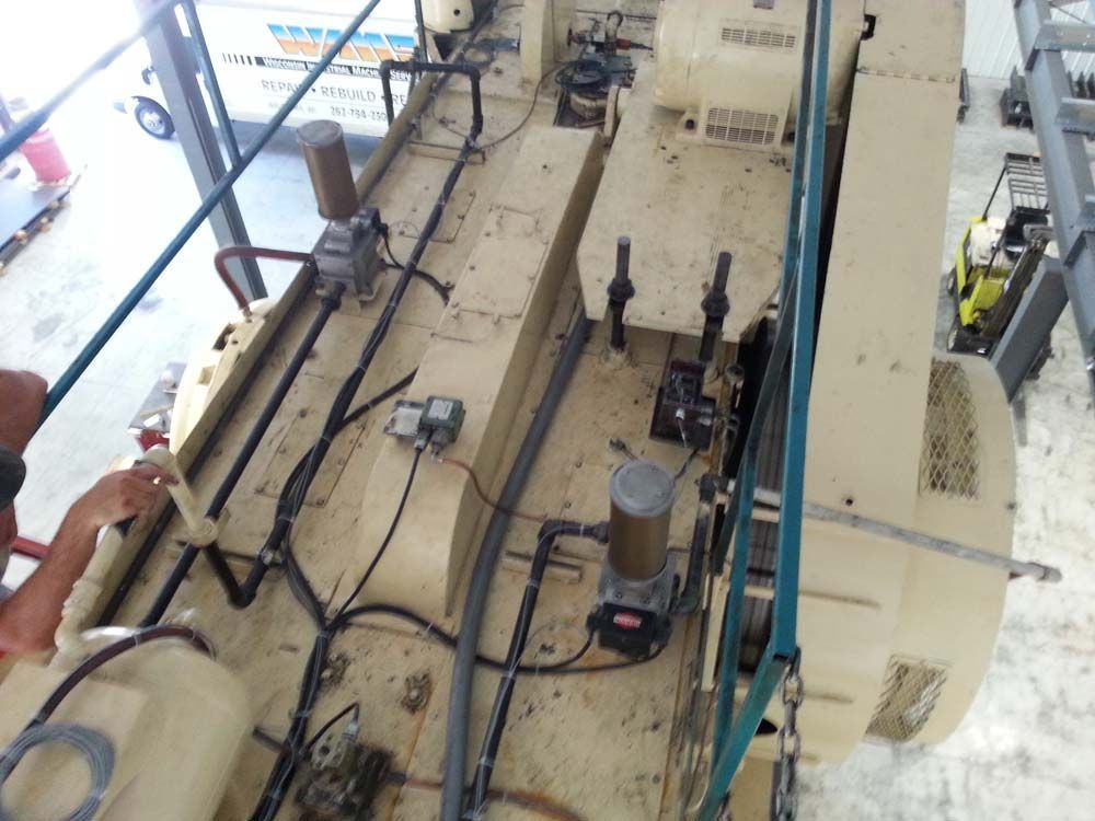 Industrial machinery with hoses and pipes in a beige maintenance area, viewed from above.