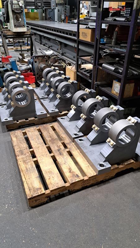 Rows of silver metal engine parts on wooden pallets in a workshop warehouse aisle