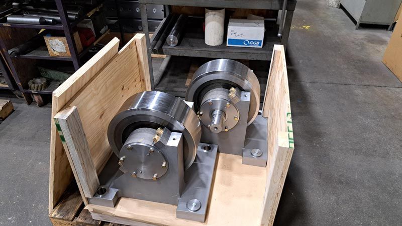 Two metal rotary chucks mounted on gray bases inside a wooden shipping crate.