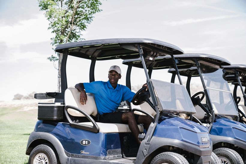 A man sitting in a blue golf cart on a golf course.