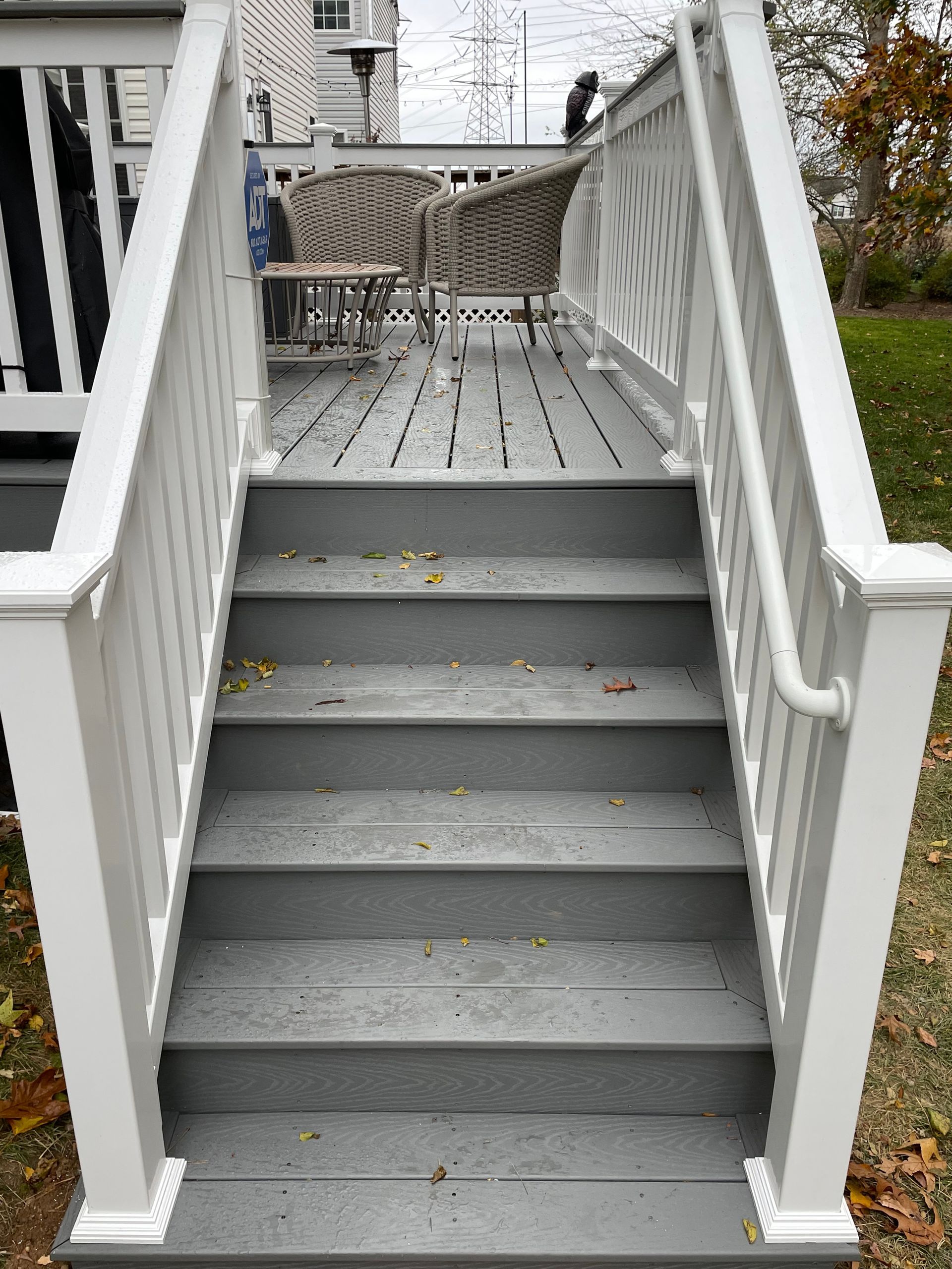 White wooden stairs leading to a front porch with a wicker table and chairs