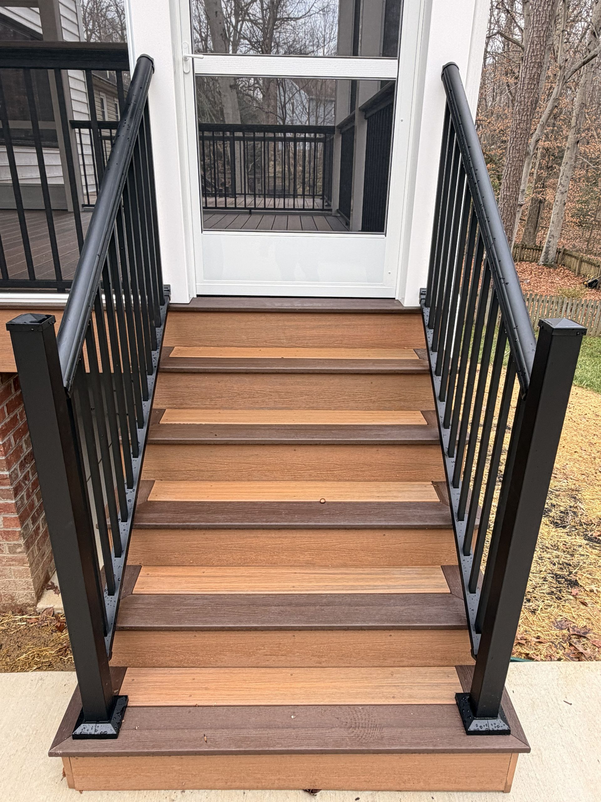 Exterior wooden steps with black railings leading up to a porch entrance