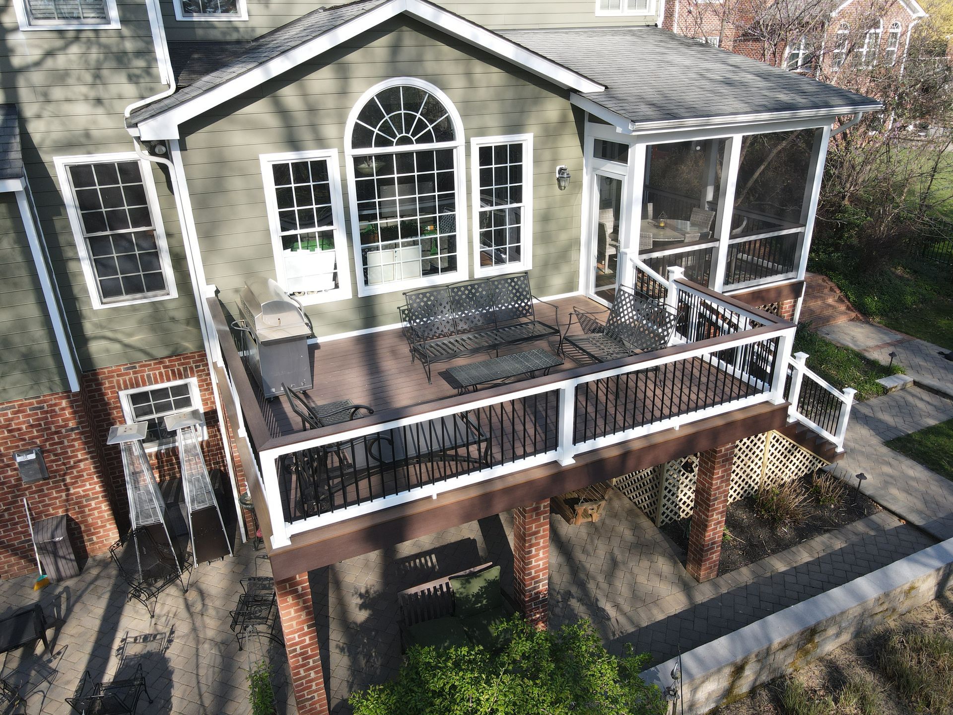 Two-story house with a large front porch, balcony, and white-trimmed windows from an elevated view