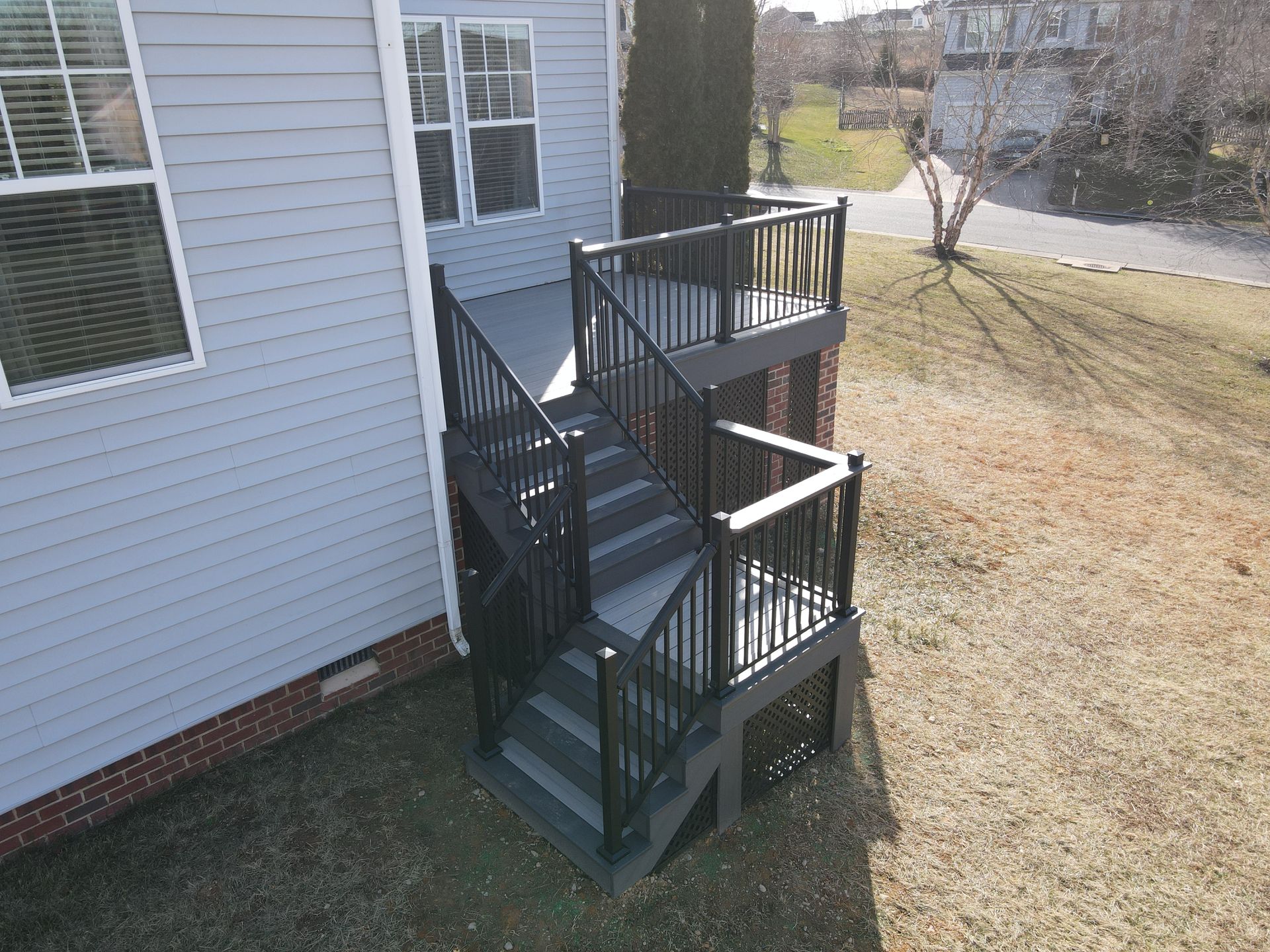 Black metal staircase and small landing attached to a gray house exterior.