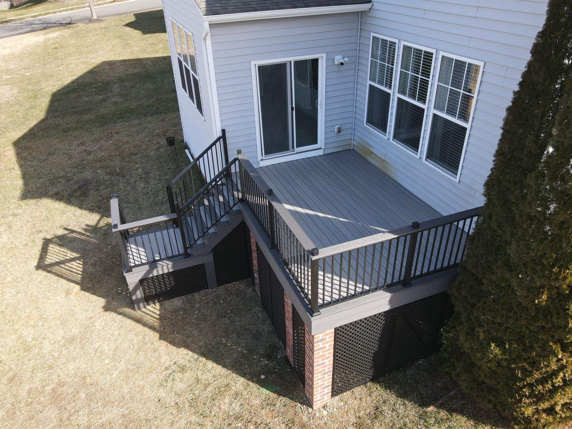 House deck with black railings and stairs beside a sliding glass door