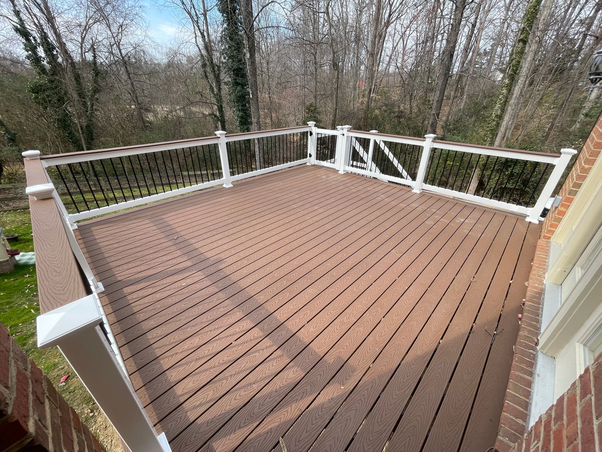 Wooden deck with white railing overlooking a wooded backyard