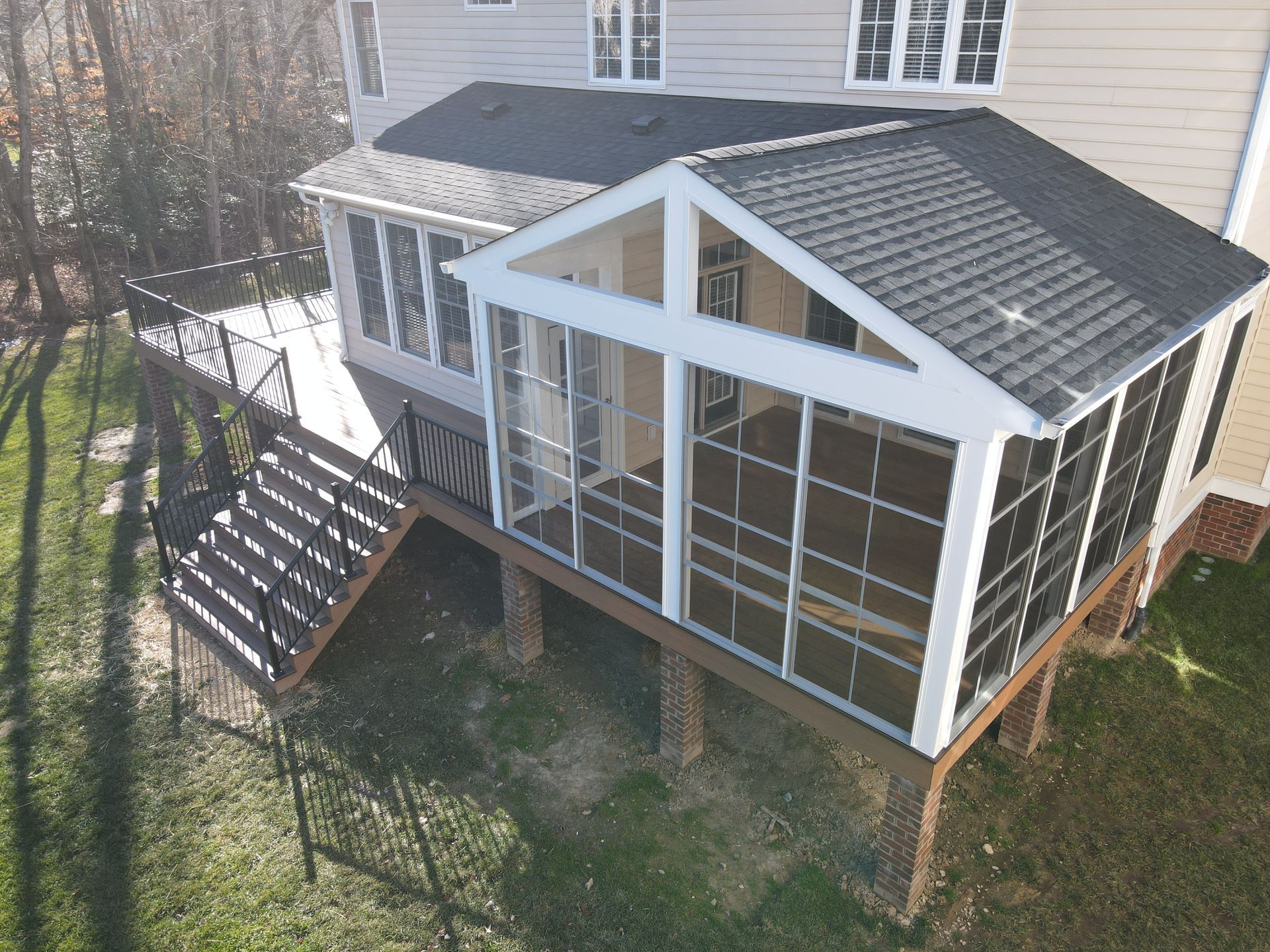 Elevated sunroom with large windows and gabled roof attached to a house, viewed from above.