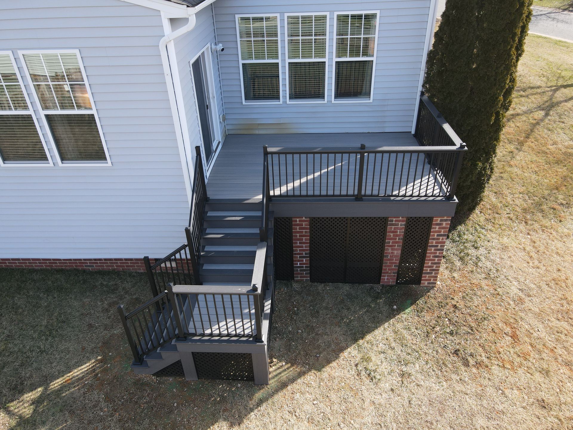 House exterior with front steps, black railing, and small deck over brick support wall