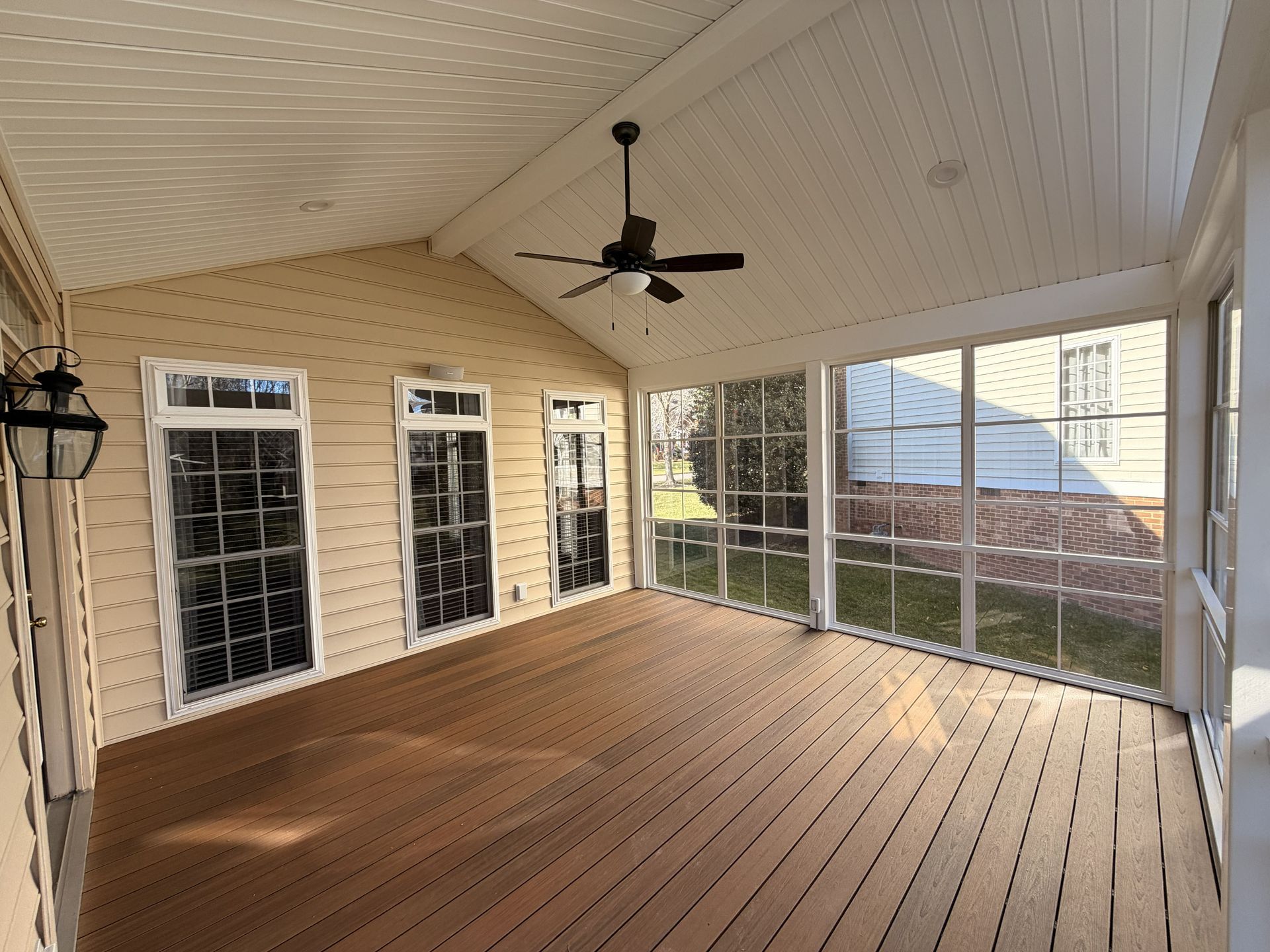 Screened porch with wood floor, white ceiling, ceiling fan, windows, and sliding glass doors.
