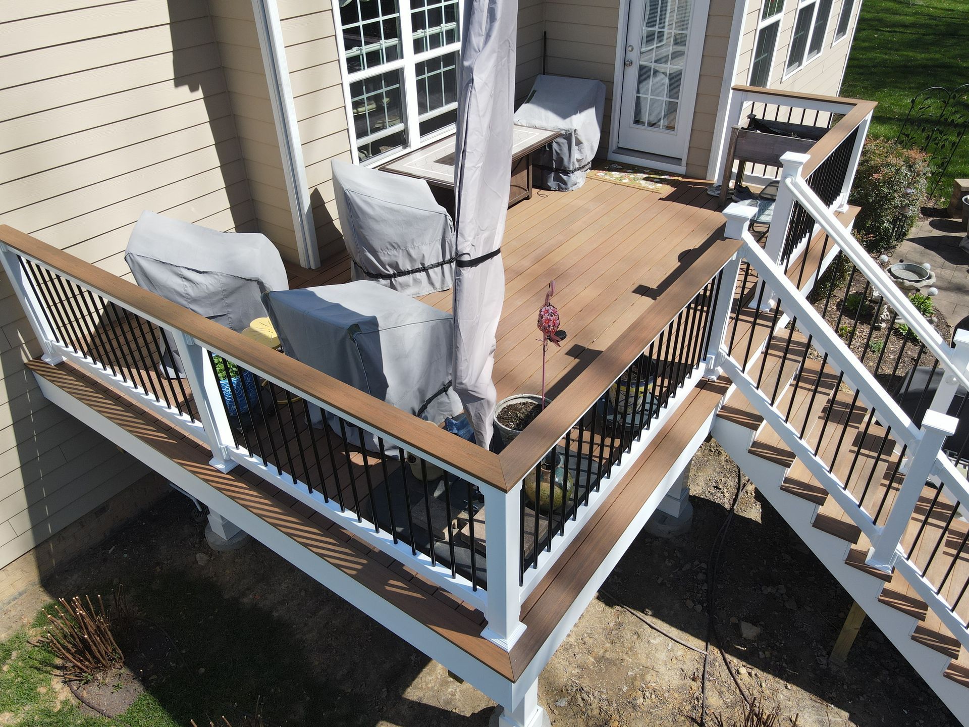 Wooden deck with gray cushioned outdoor chairs and table beside a house, viewed from above