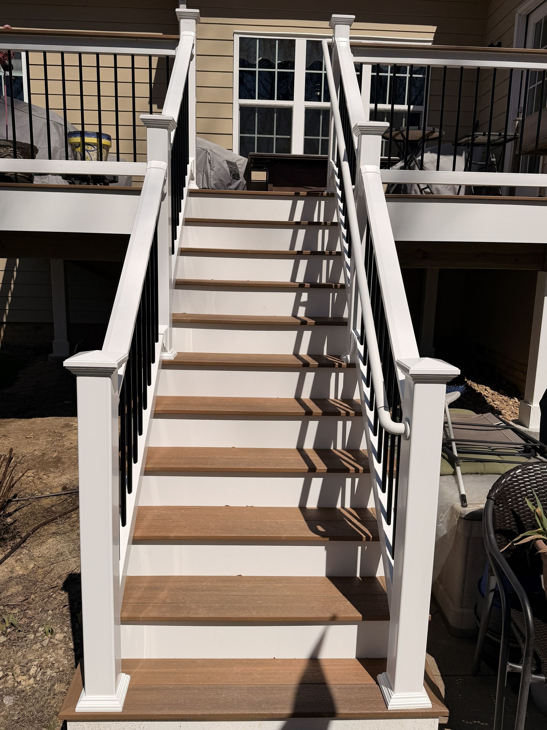 Front steps and staircase with white railings leading to a house porch