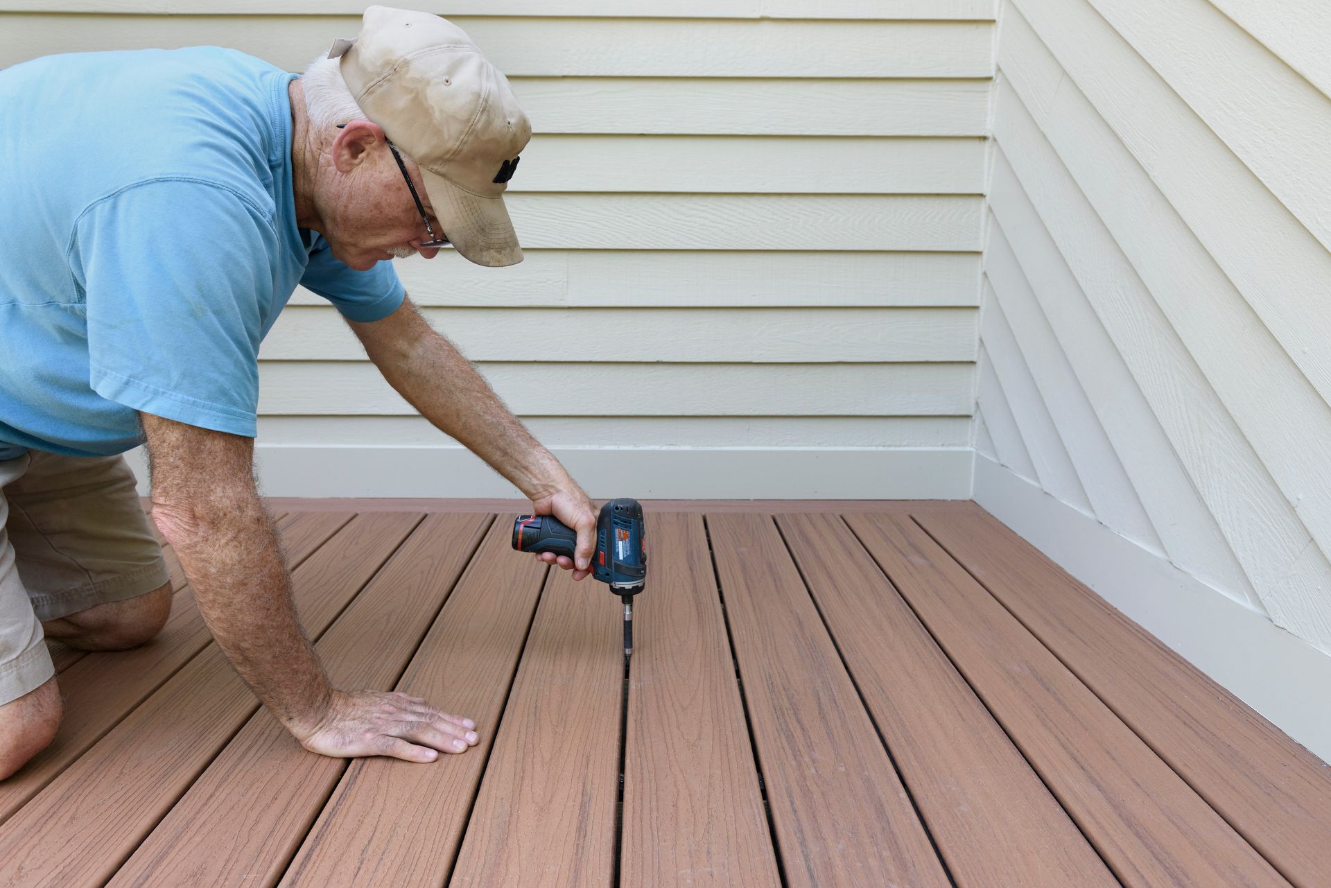 Person using a drill to install decking boards on a porch floor