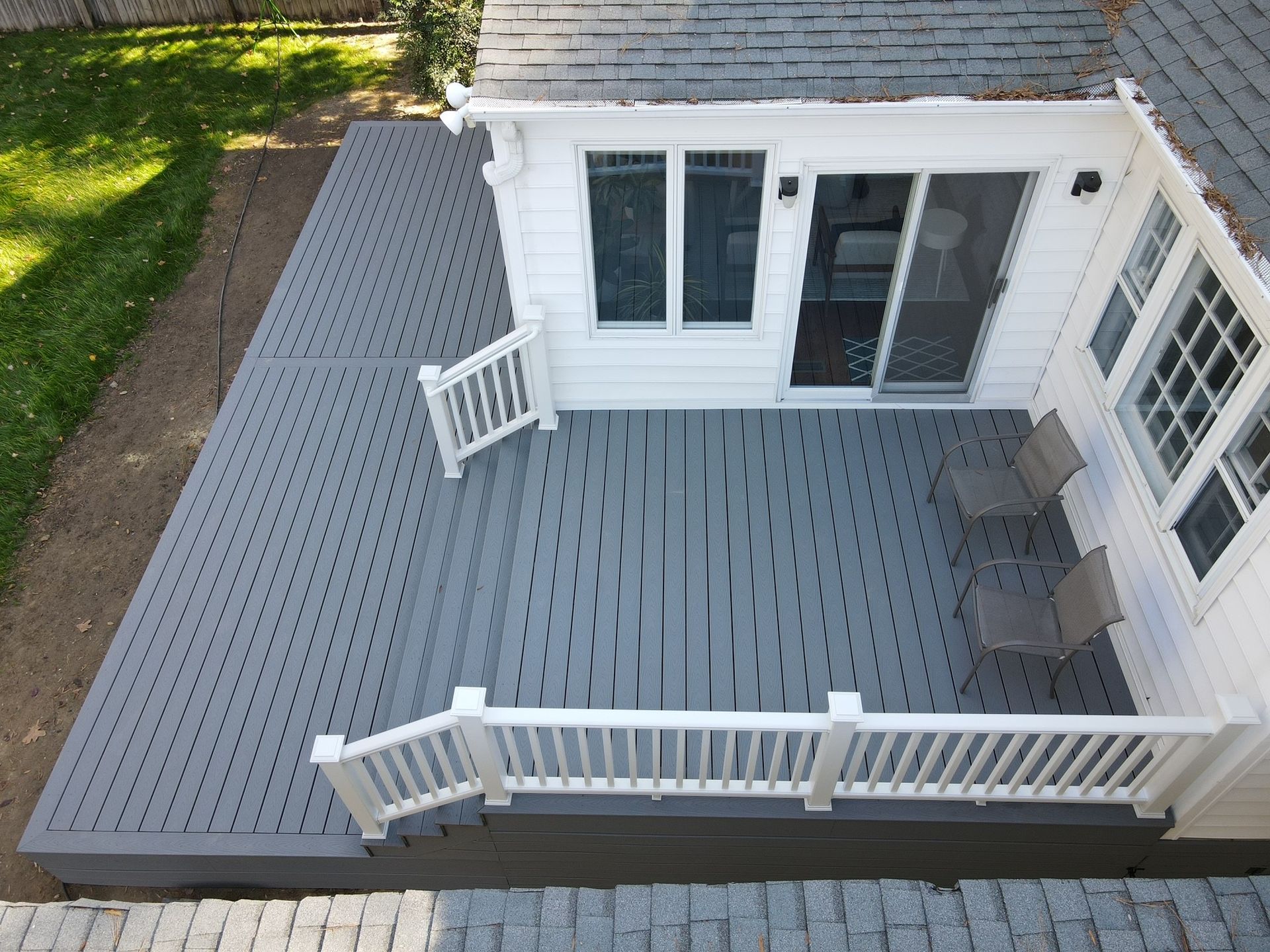 White deck with railings beside a house, viewed from above.