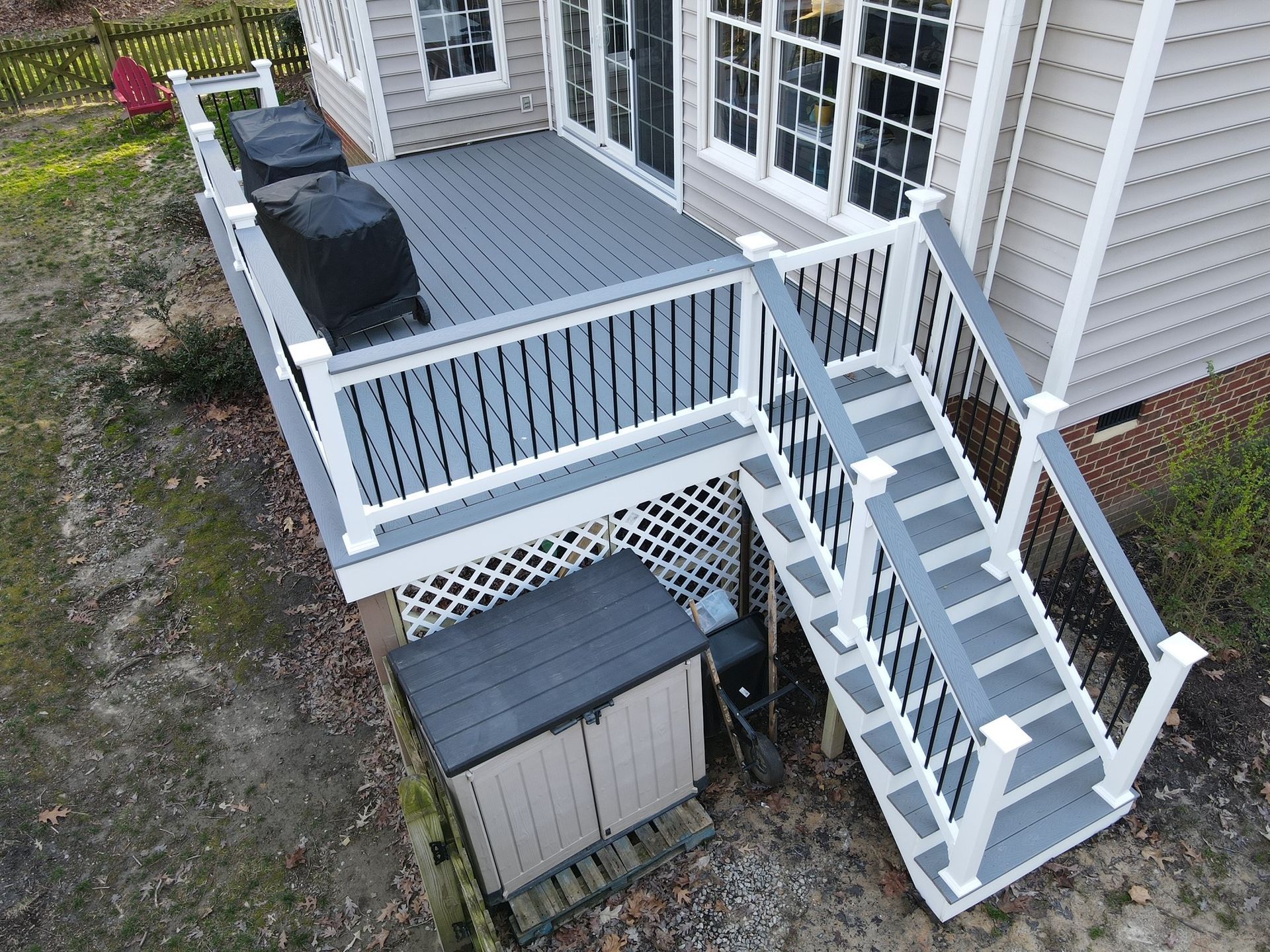 White accessibility ramp and stairs leading to a house deck, with a small shed below.