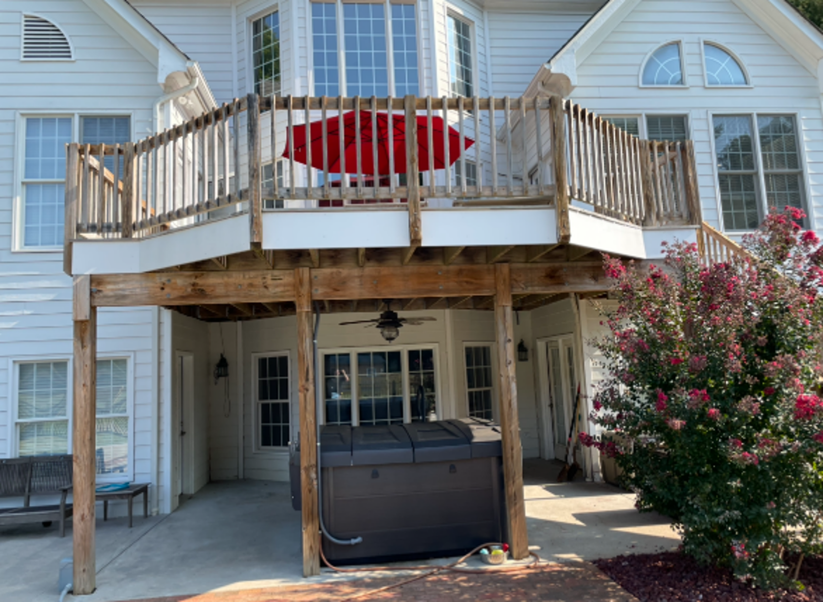 Elevated backyard deck with railings, patio furniture, and a hot tub below.
