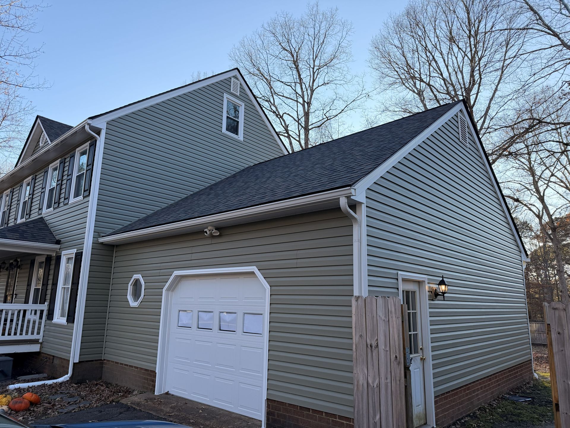 Suburban house exterior with gray siding, white garage door, and small fenced side yard