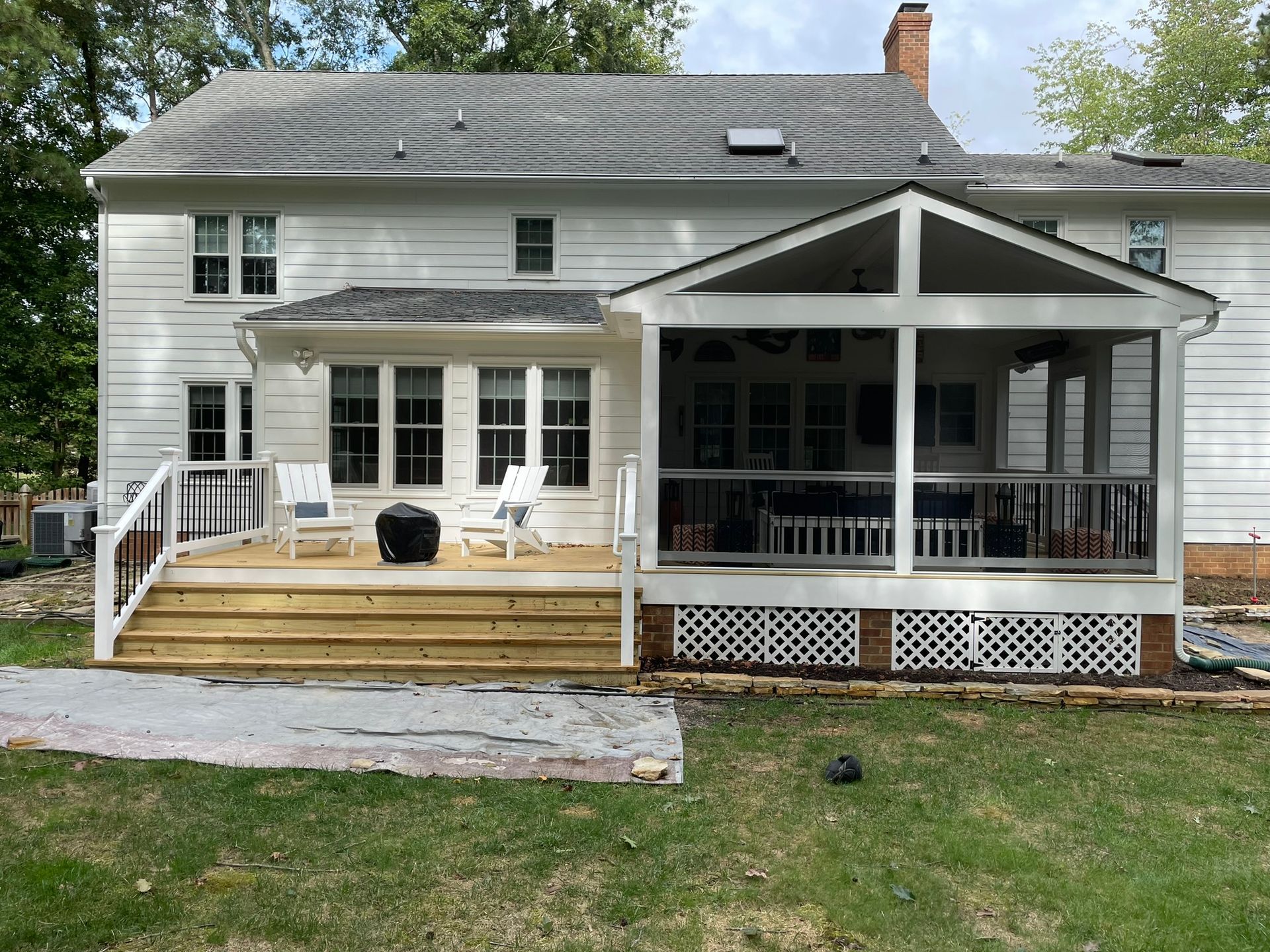 White two-story house with a screened porch, wooden deck steps, and a grassy yard